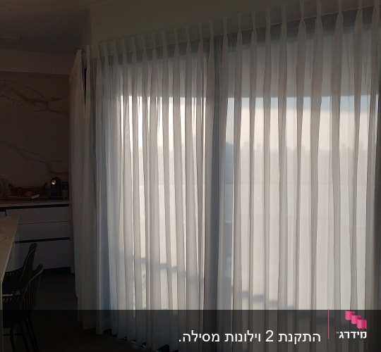 וילונות לבנים תלויים על חלון גדול